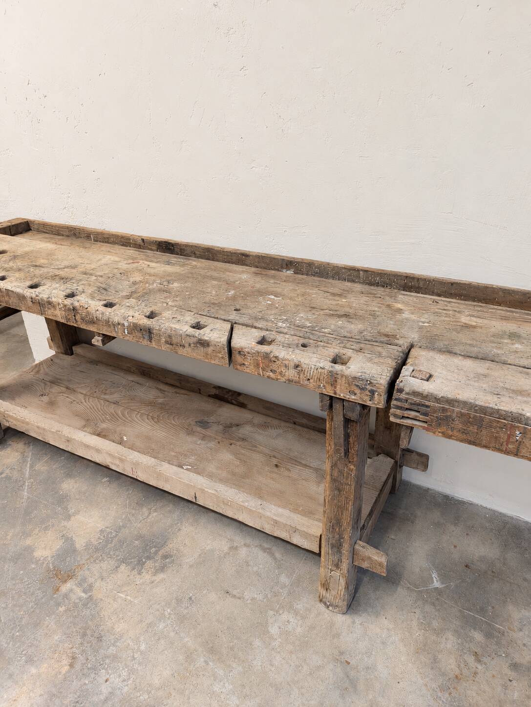 Antique wooden workbench with a vice and drawer.
