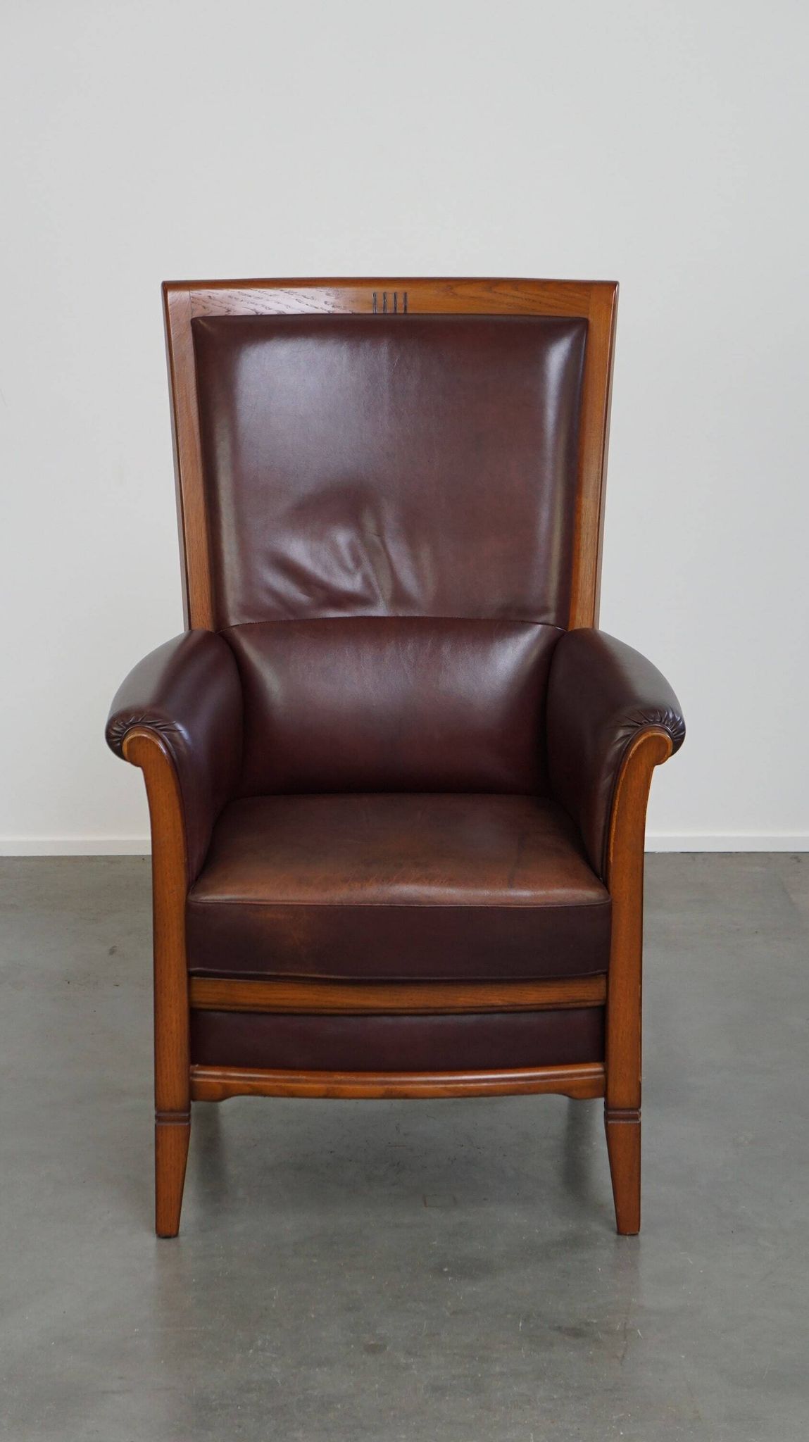 Very comfortable classic cowhide armchair with a high back in a mild Art Deco style