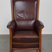 Very comfortable classic cowhide armchair with a high back in a mild Art Deco style