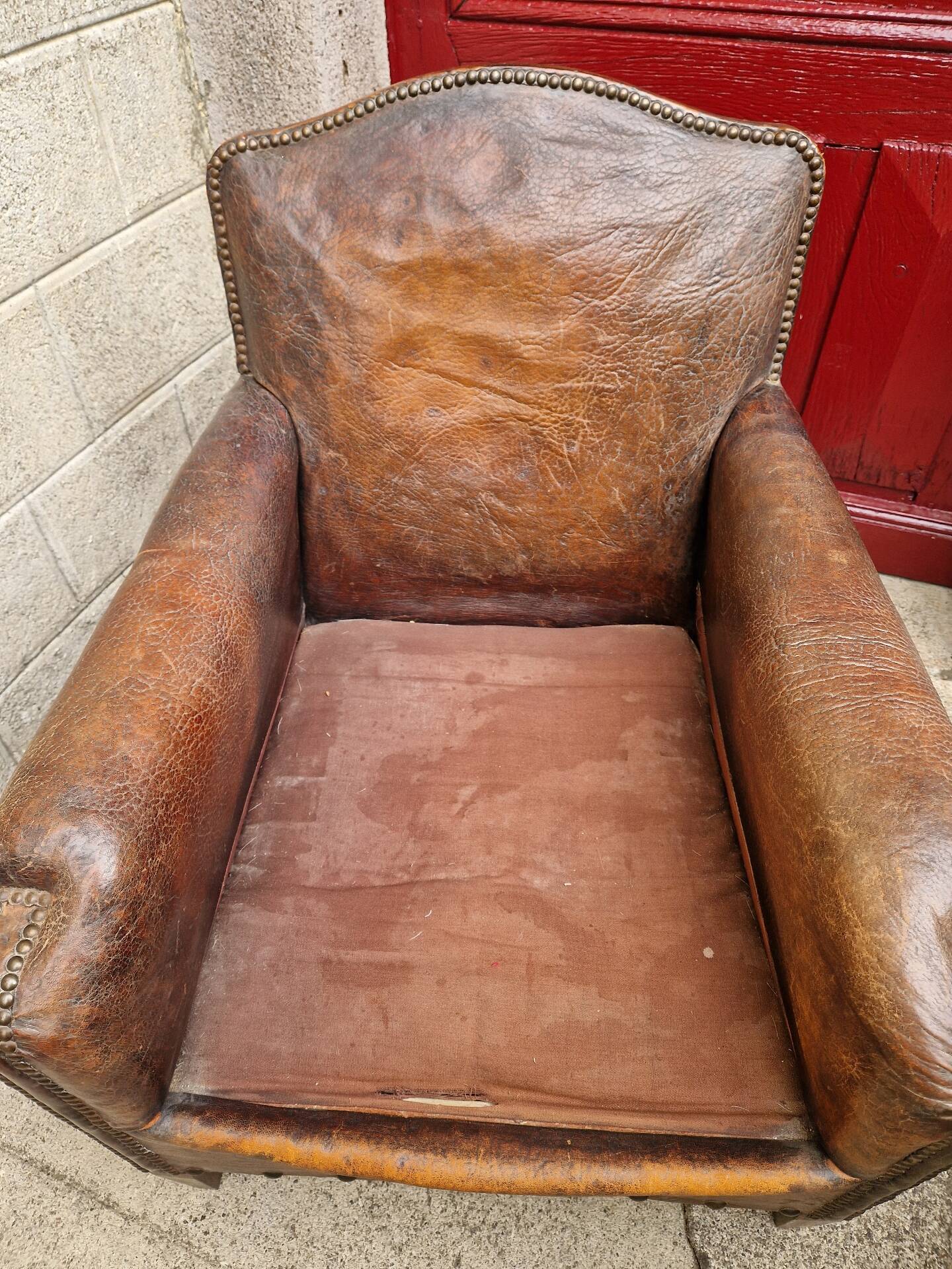 Antique club chair in patinated brown leather, early 20th century English style.