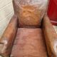 Antique club chair in patinated brown leather, early 20th century English style.