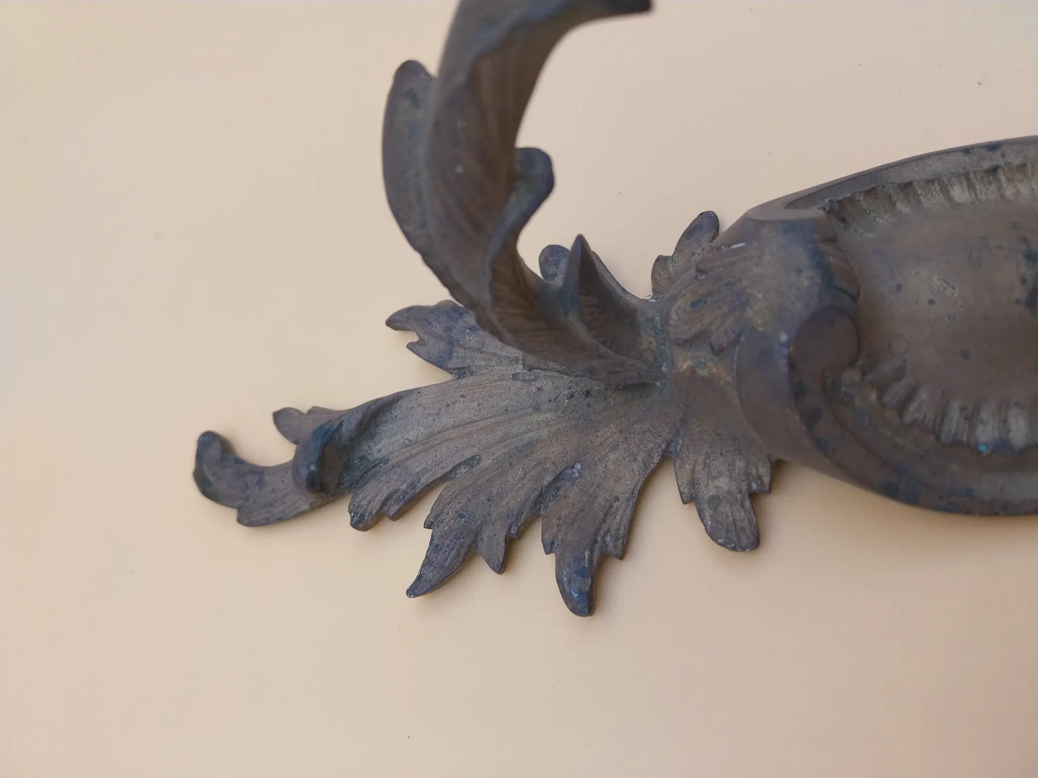 Pair of wall sconces in bronze candle holders with leaf medallion decoration.
