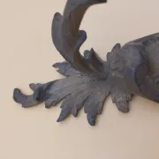 Pair of wall sconces in bronze candle holders with leaf medallion decoration.
