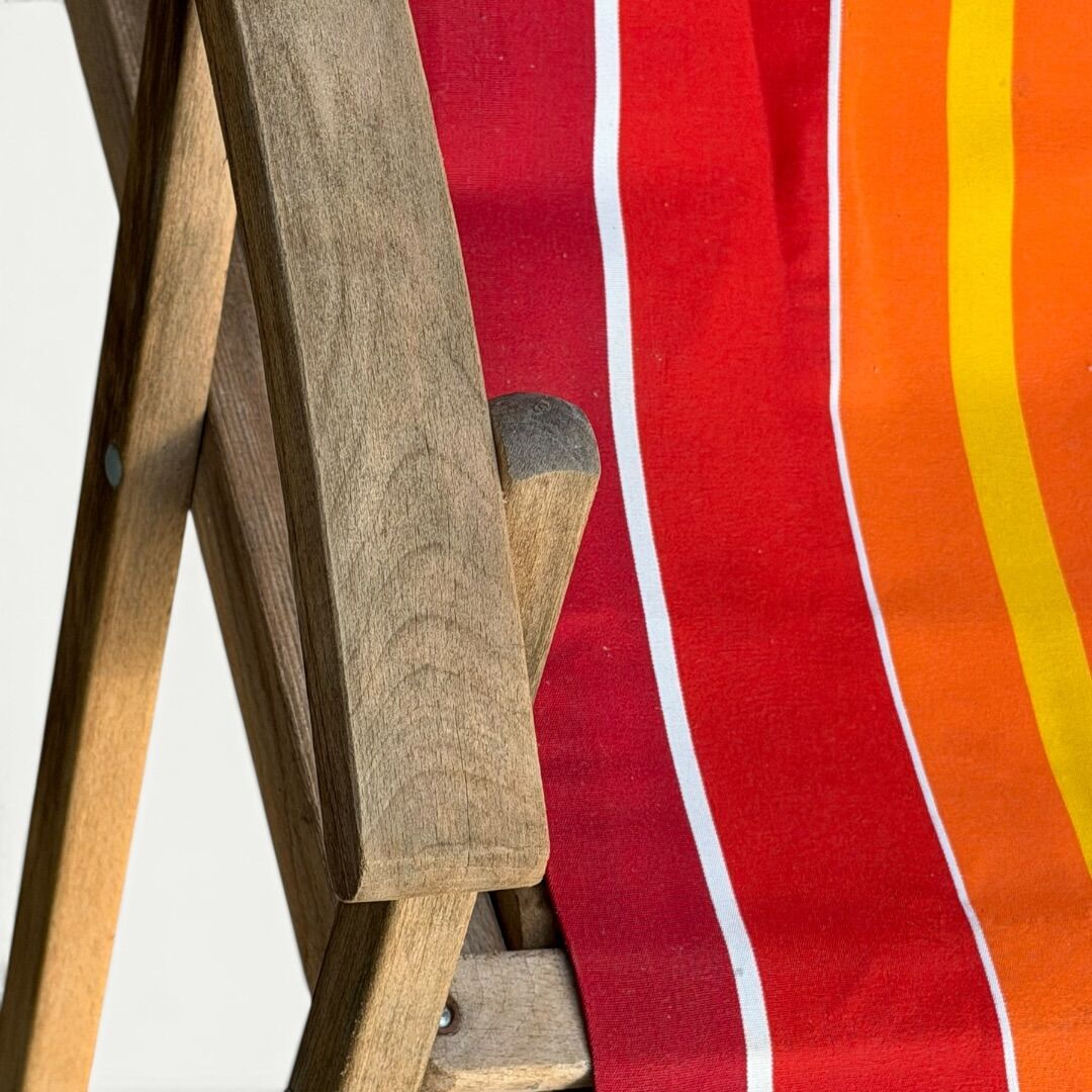 Vintage deck chair with red and orange striped fabric, original patina.