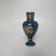 Small turquoise blue and gold porcelain vase with elegant floral patterns.