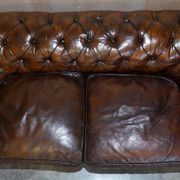 Victorian Chesterfield leather upholstered canapé with feather cushions.