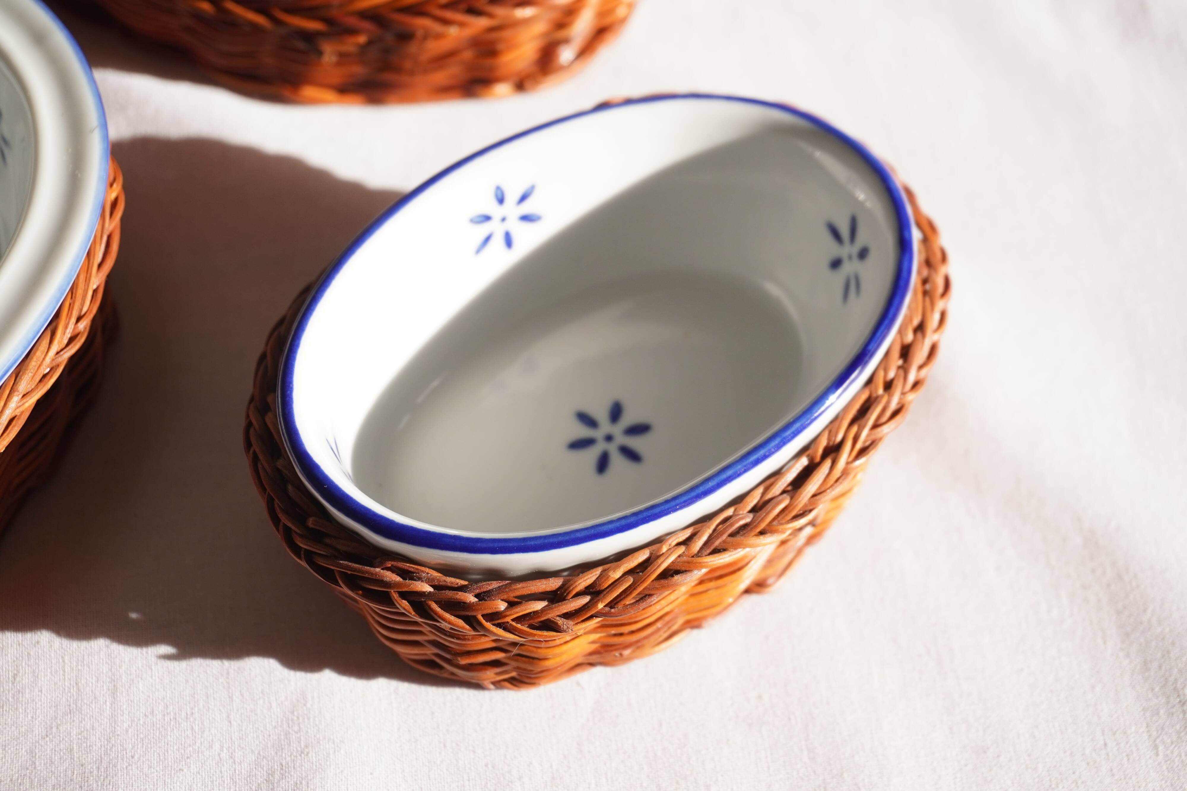 Set of 4 white porcelain dishes with blue decorations and wicker stands