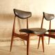 Pair of modernist Scandinavian chairs in teak and black faux leather.