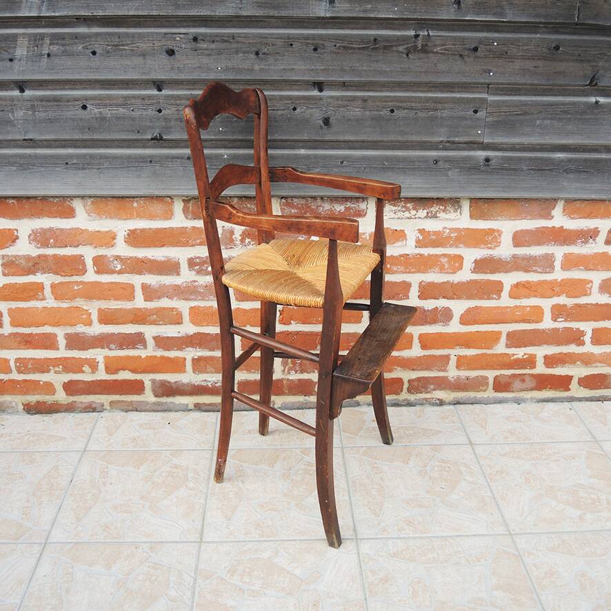 Old wooden high chair for children with straw.