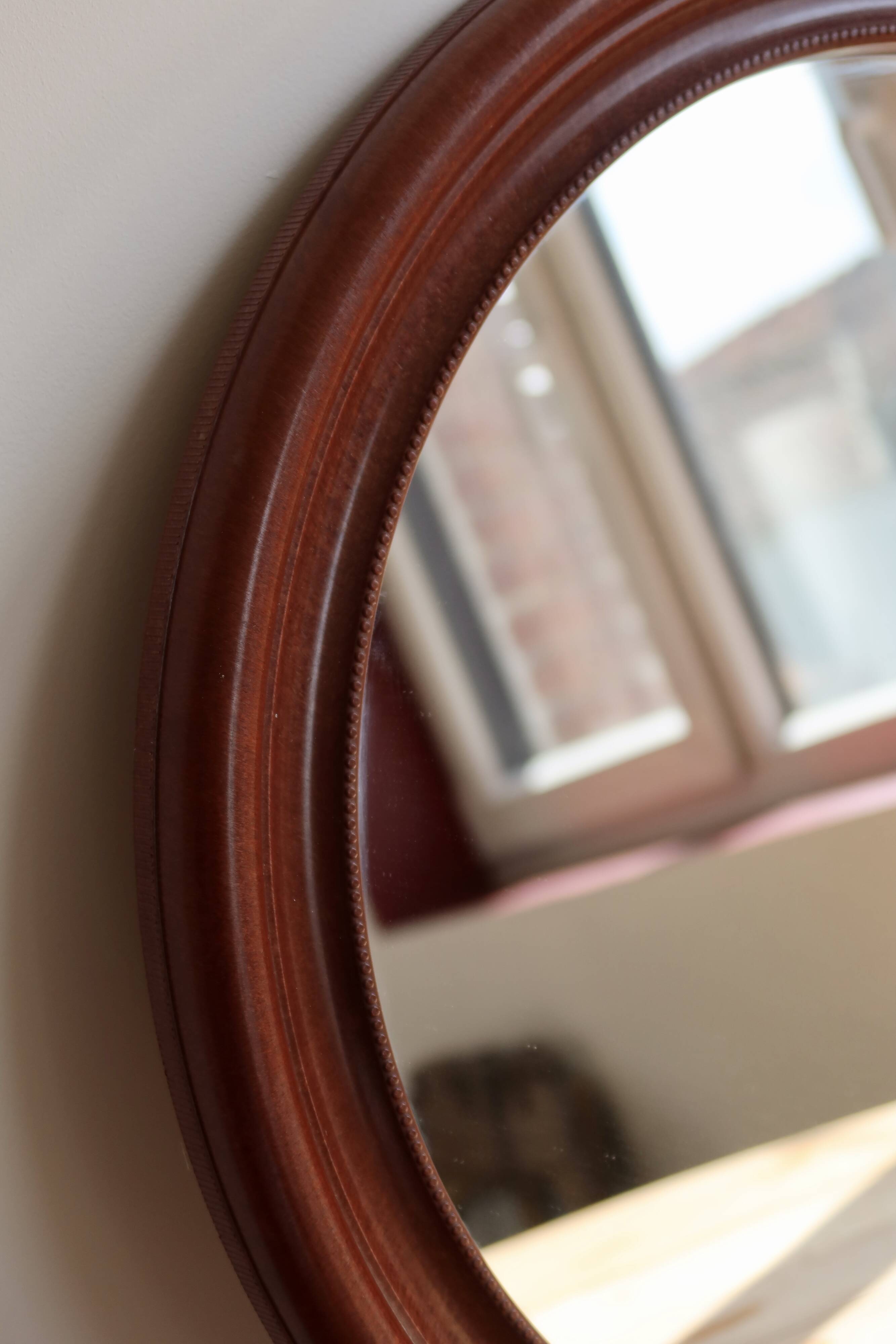 Round vintage mirror with mahogany wood effect frame.