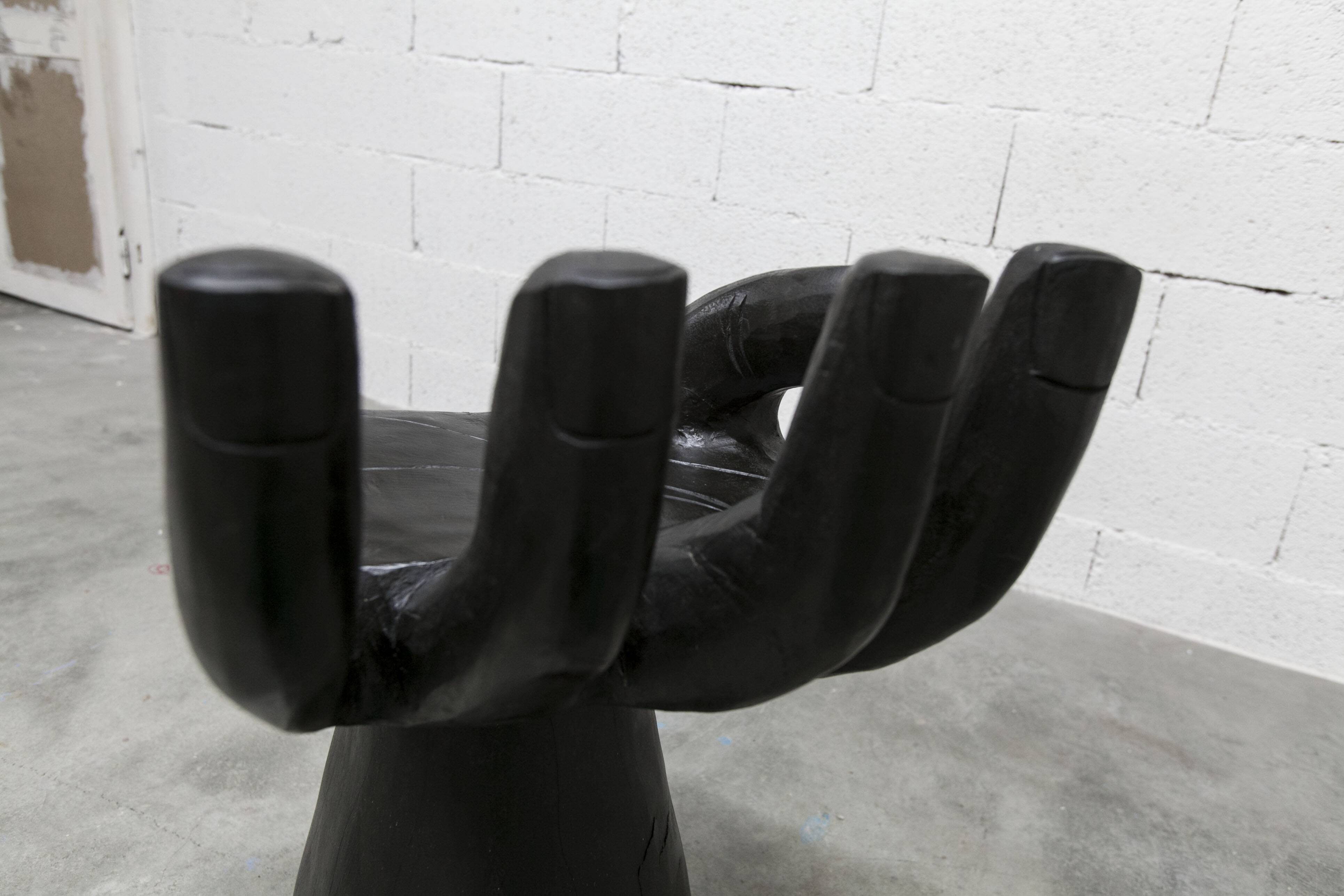 Black armchair chair in carved wood in the shape of a hand