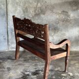 Small antique Indonesian bench in carved teak with plant and floral motifs.