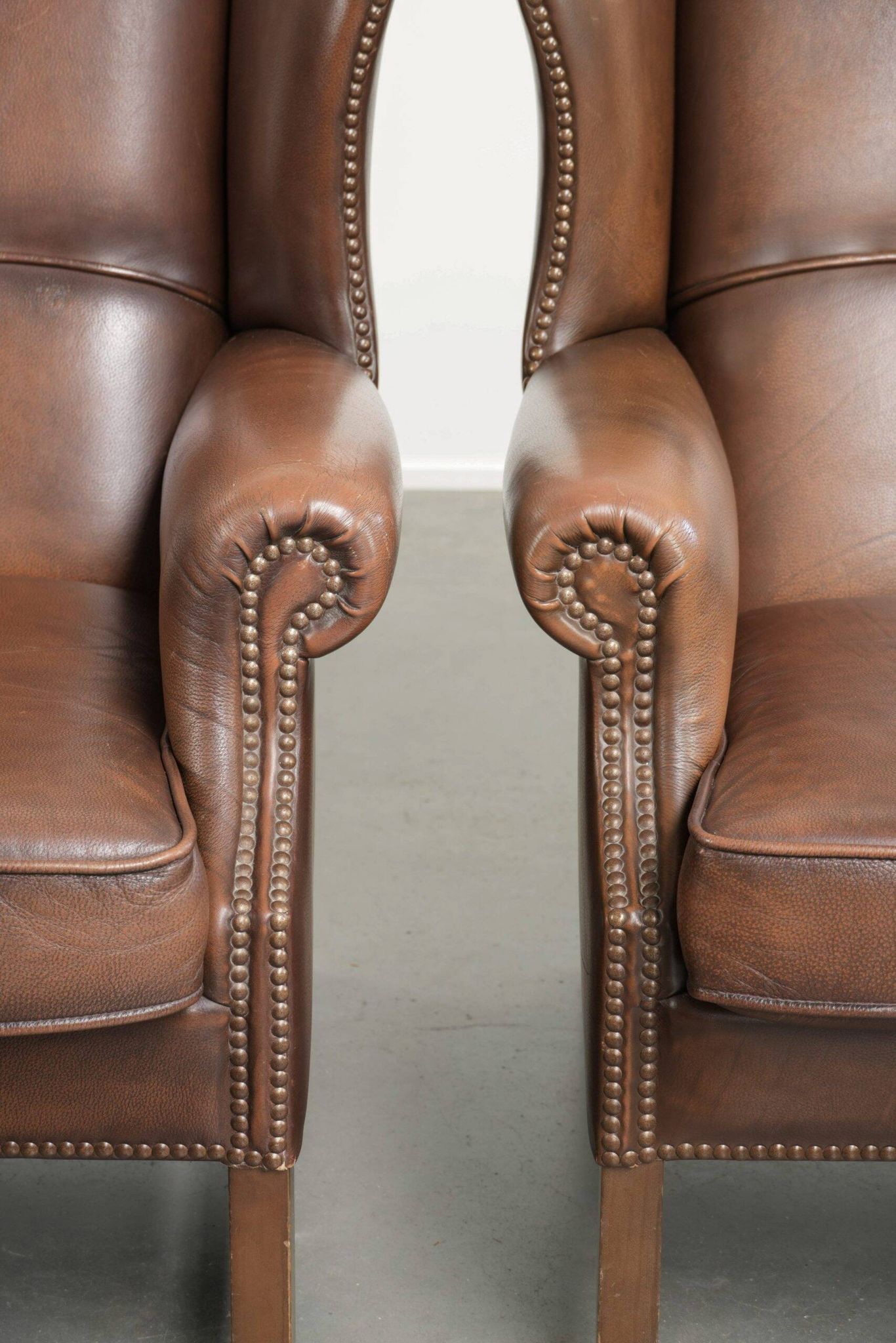 Ensemble de 2 fauteuils à oreilles en cuir de vache de style anglais.