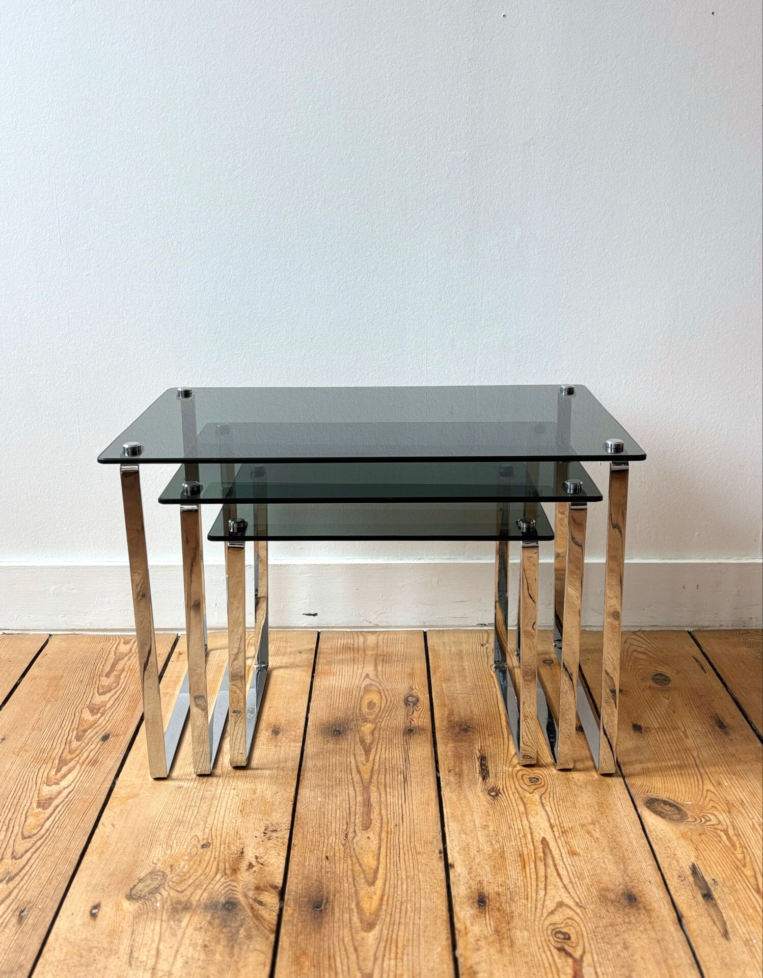 Nest of coffee tables in chrome with smoked glass top.