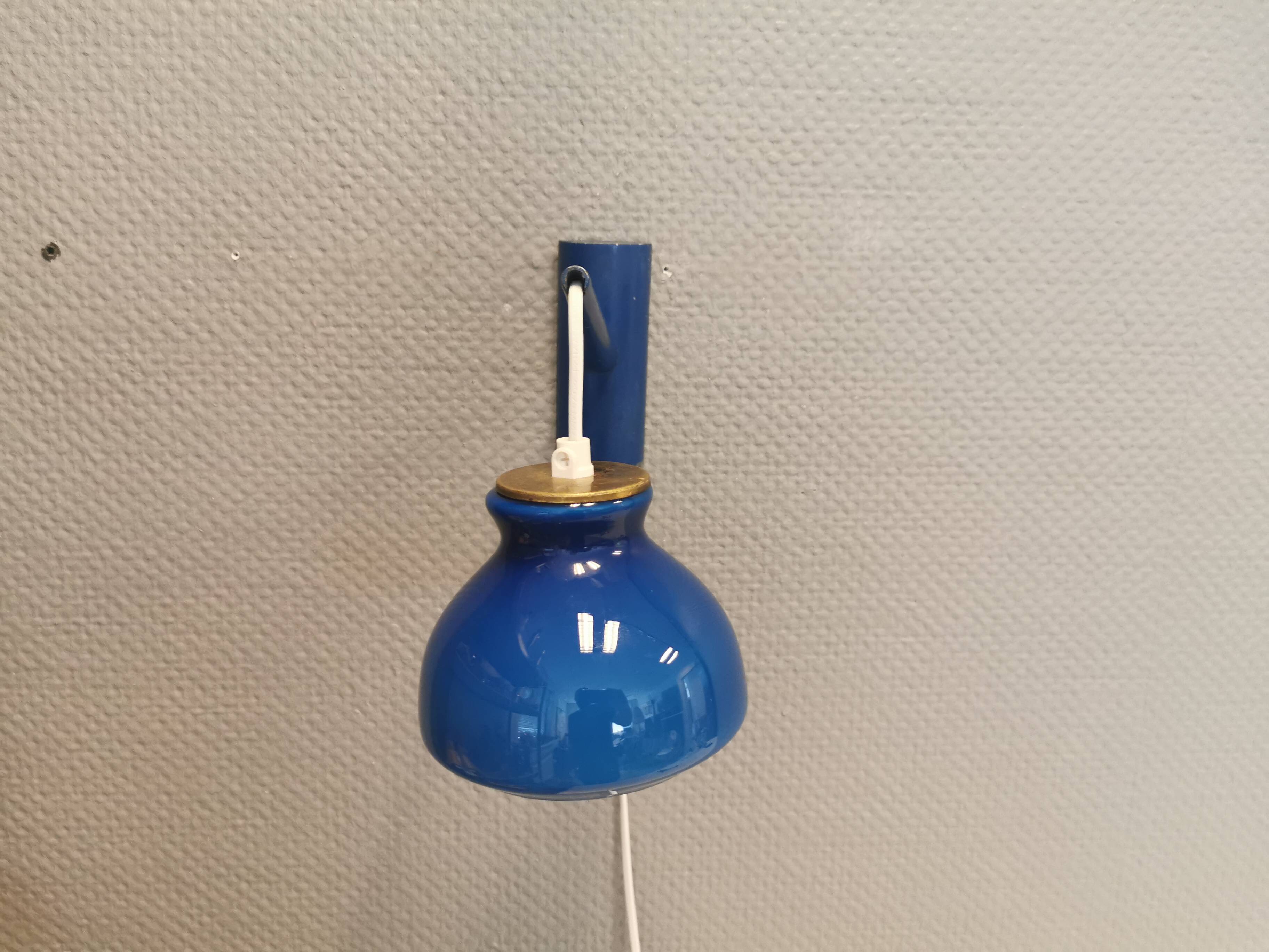 Applique Holmegaard avec abat-jour en verre et détail en laiton sur le dessus. Support mural en bois peint en bleu