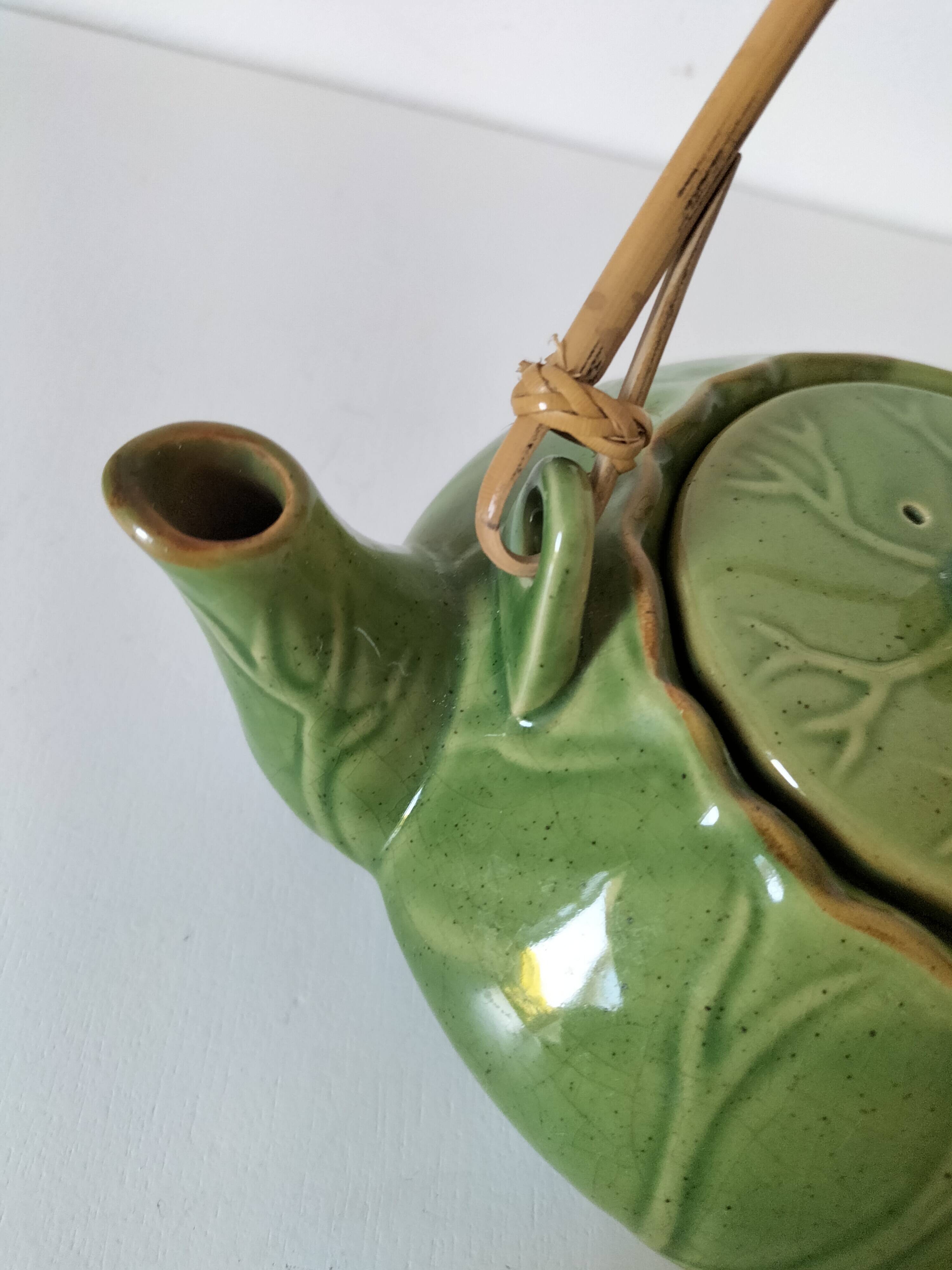 Vintage green teapot with lotus decoration and bamboo handle.