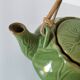 Vintage green teapot with lotus decoration and bamboo handle.
