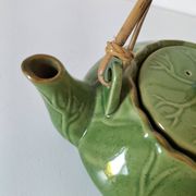 Vintage green teapot with lotus decoration and bamboo handle.