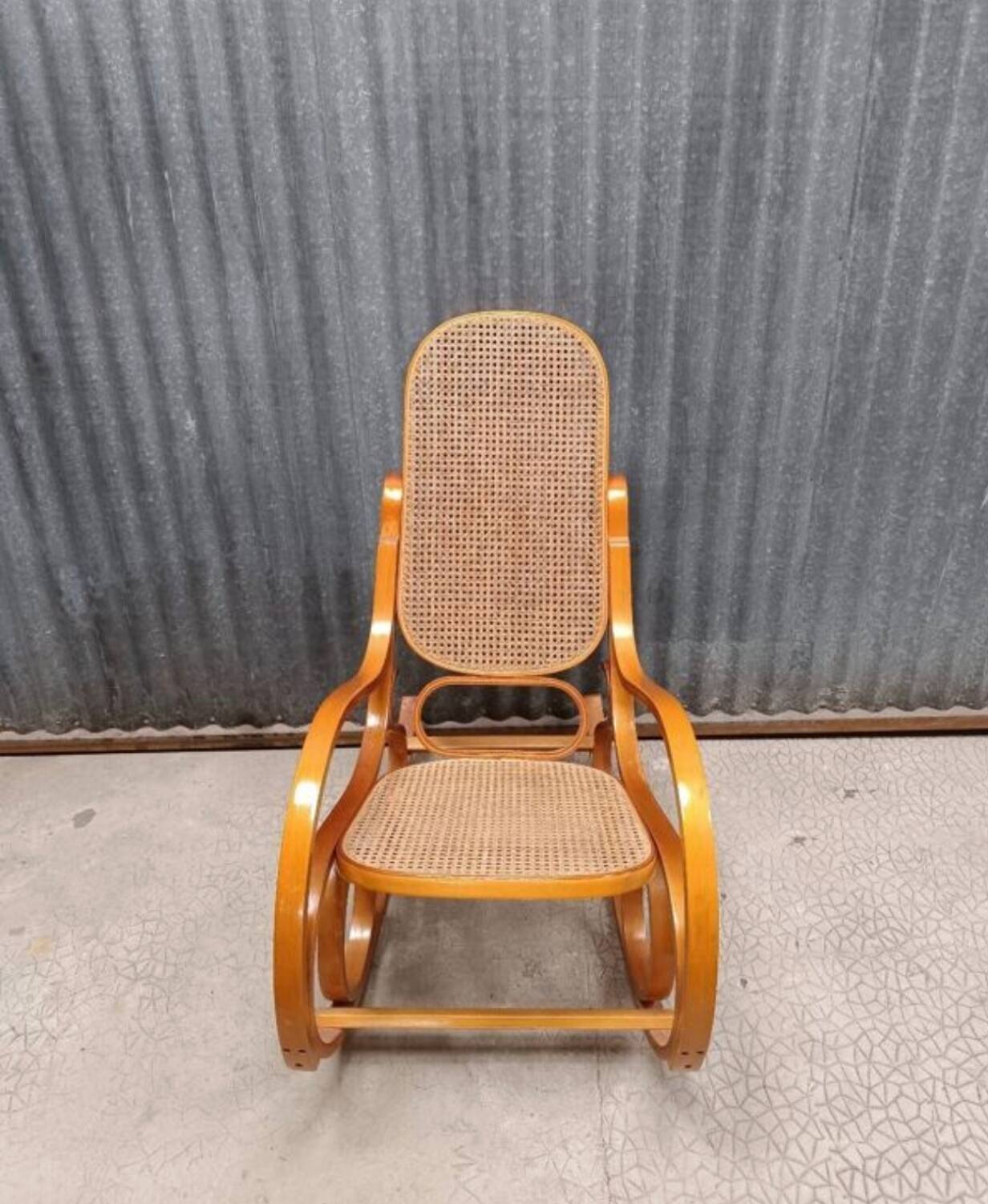 Curved wooden rocking chair with wicker cane rattan.