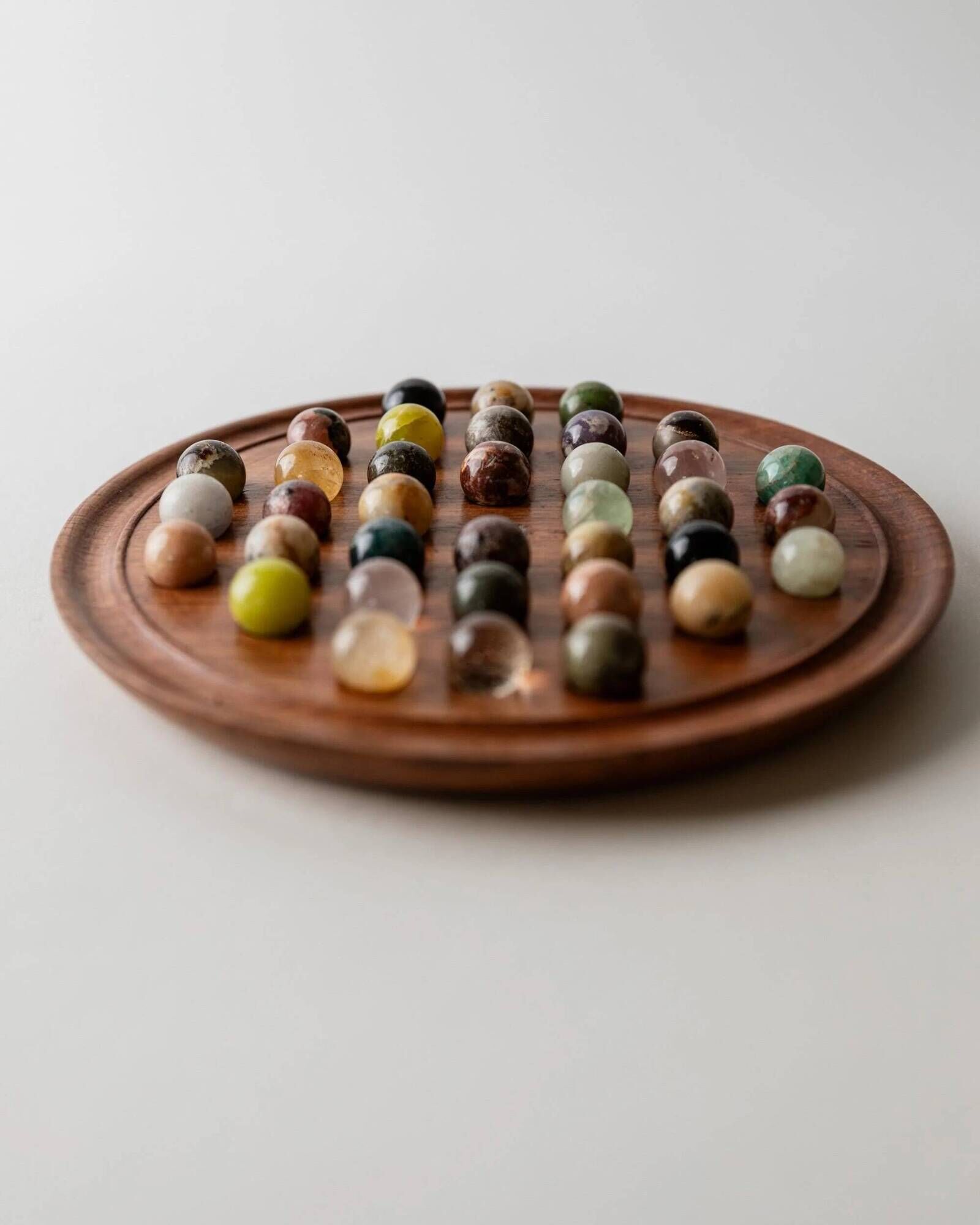 Vintage 1960s solitaire game, wooden board with stone marbles.