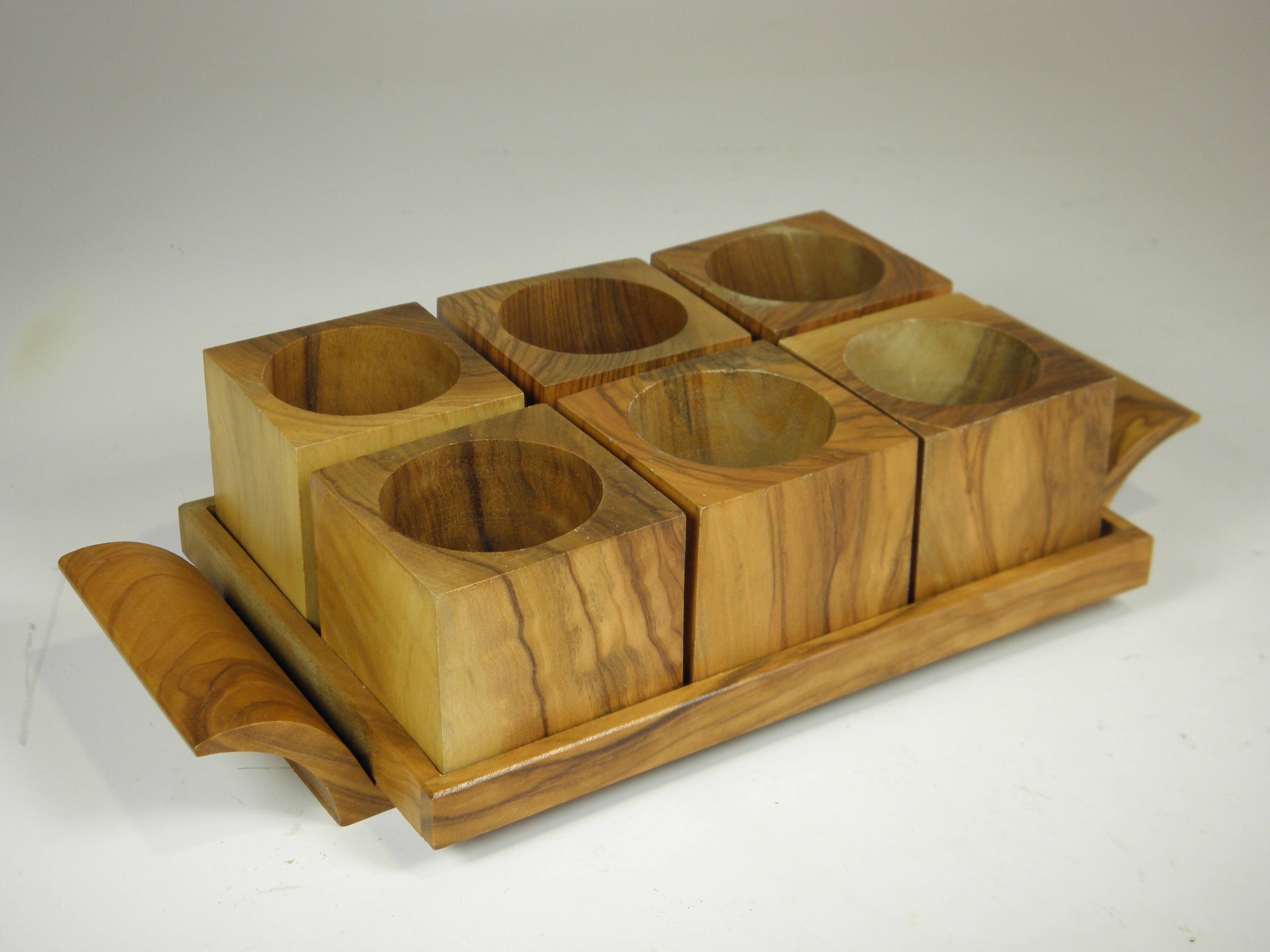 Six egg cups on a wooden tray.