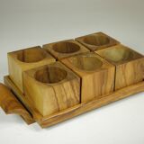 Six egg cups on a wooden tray.