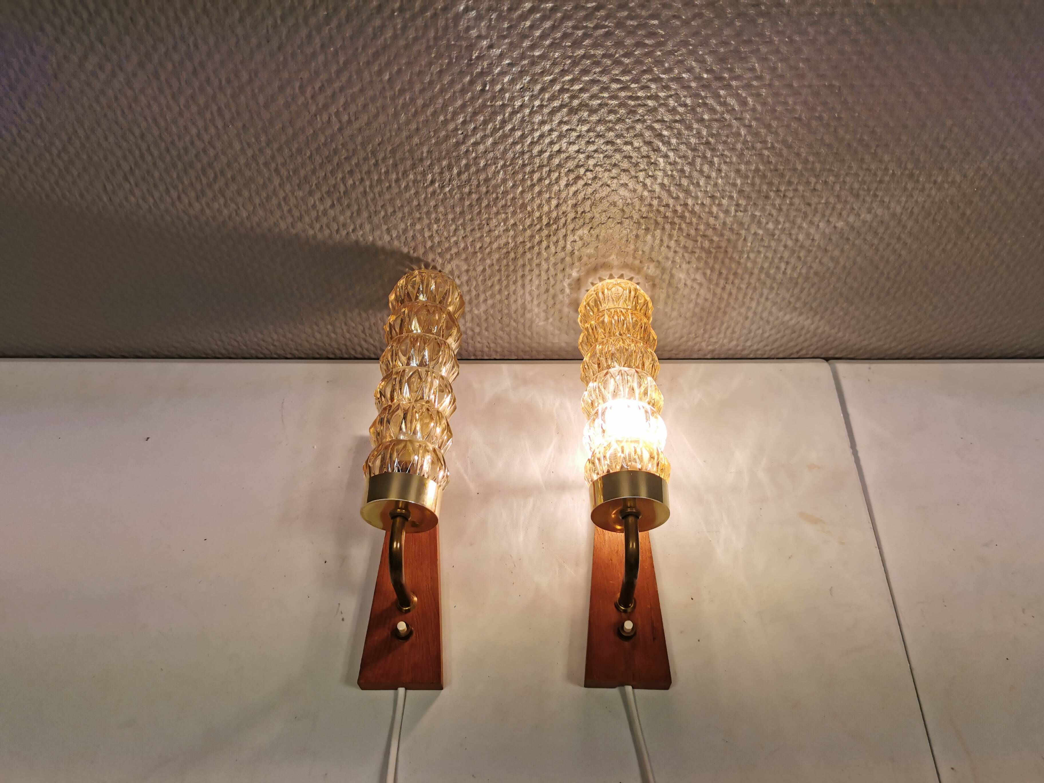 A set of Danish wall lights in champagne coloured glass with brass and teak.