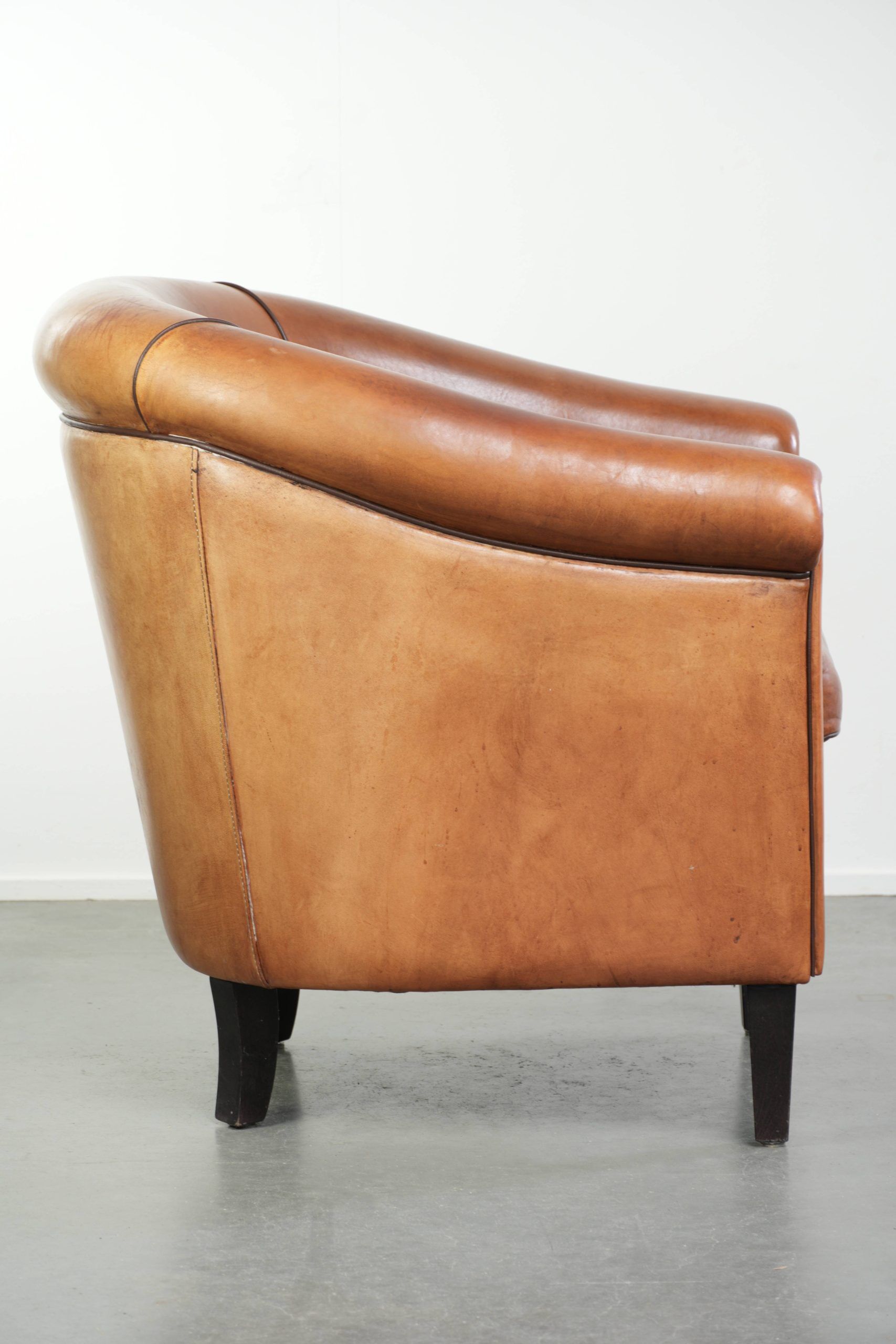Vintage sheepskin club armchair with a warm colour scheme with black piping