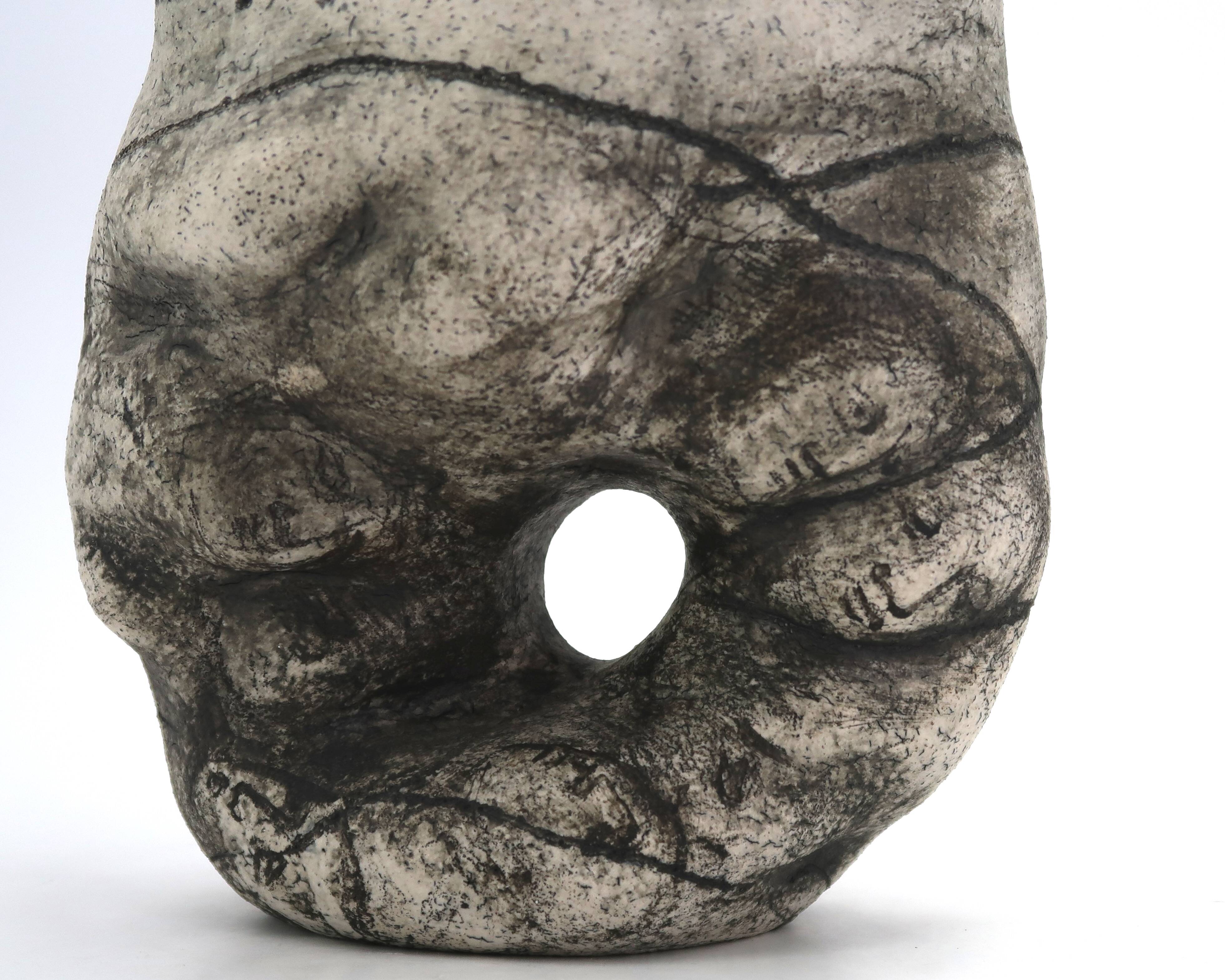 Ceramic vase sculpture decorated with faces and featuring a hole, 1980s.