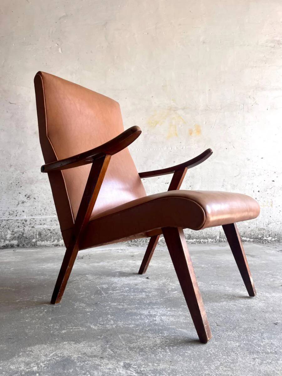 Vintage armchair from the 1950s in cognac leather and dark wood — modernist lounge chair.