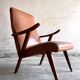 Vintage armchair from the 1950s in cognac leather and dark wood — modernist lounge chair.