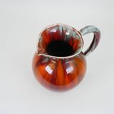 Large red and blue glazed ceramic pitcher signed Delène under the base