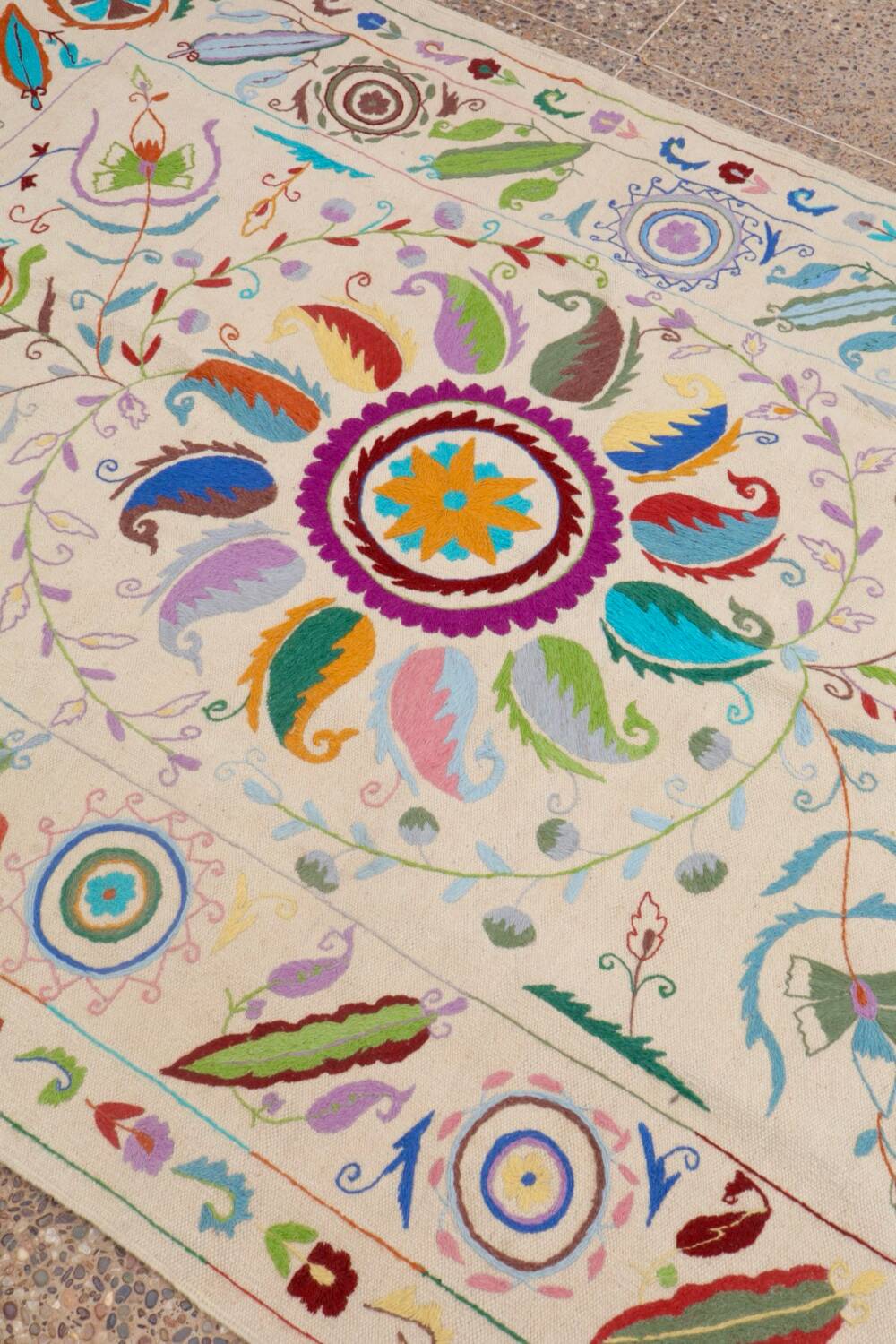 White suzani kilim rug with embroidered multi-colored patterns