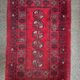 Bukhara Oriental carpet in wool with geometric patterns on a red background,