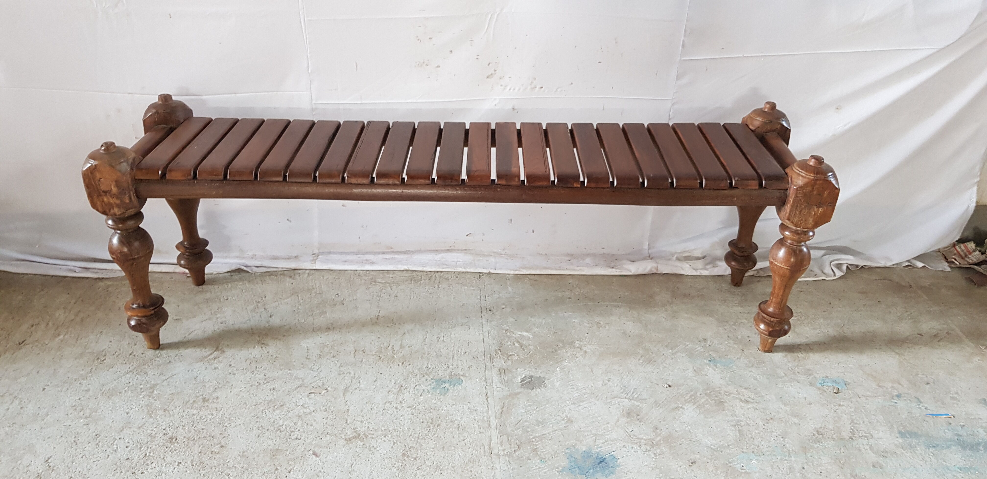 Bench with slats and feet of charpoy beds in teak