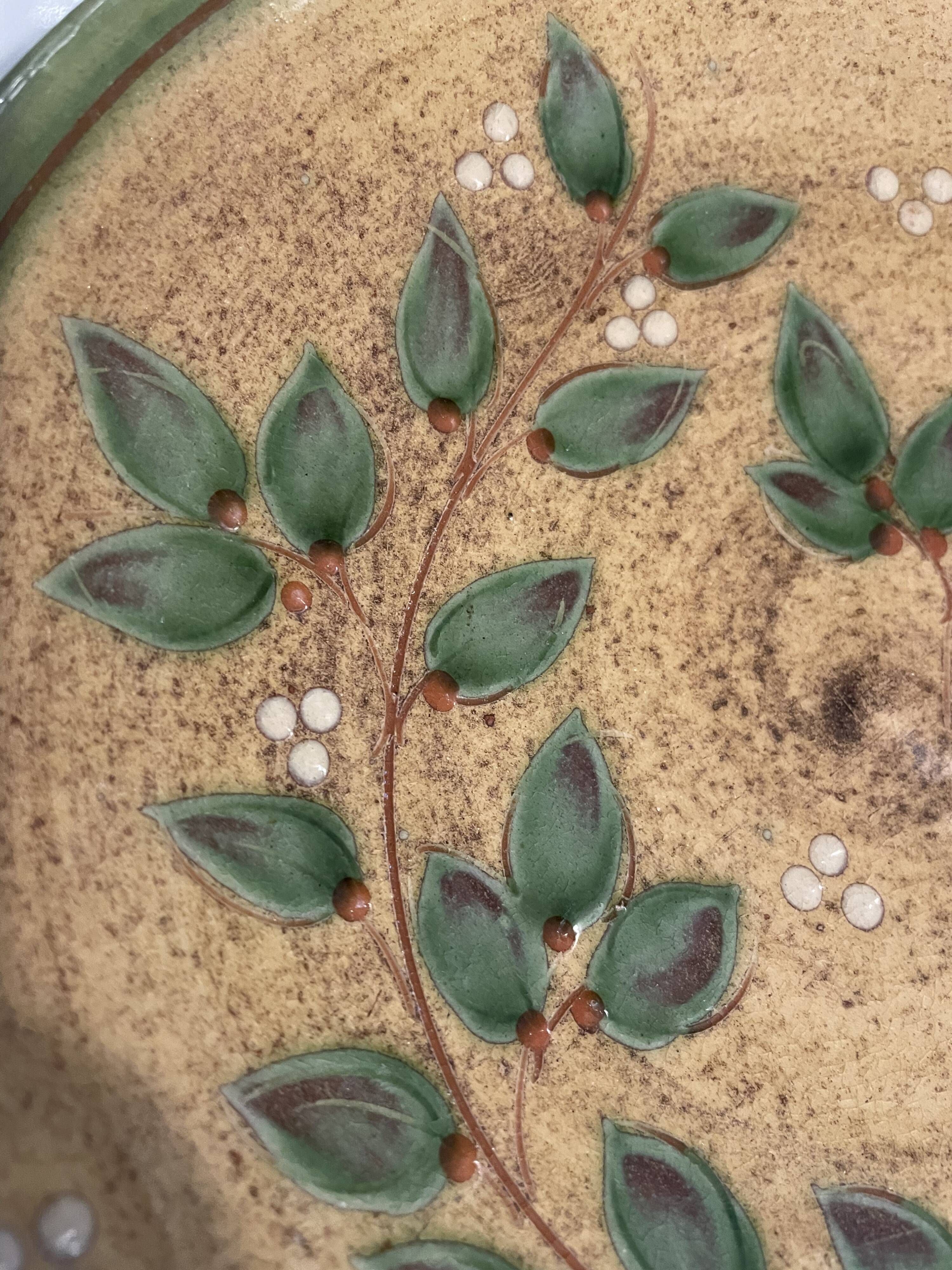 Decorative glazed terracotta plate with olive leaf pattern.