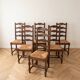 Set of 6 rustic wooden chairs with woven straw.