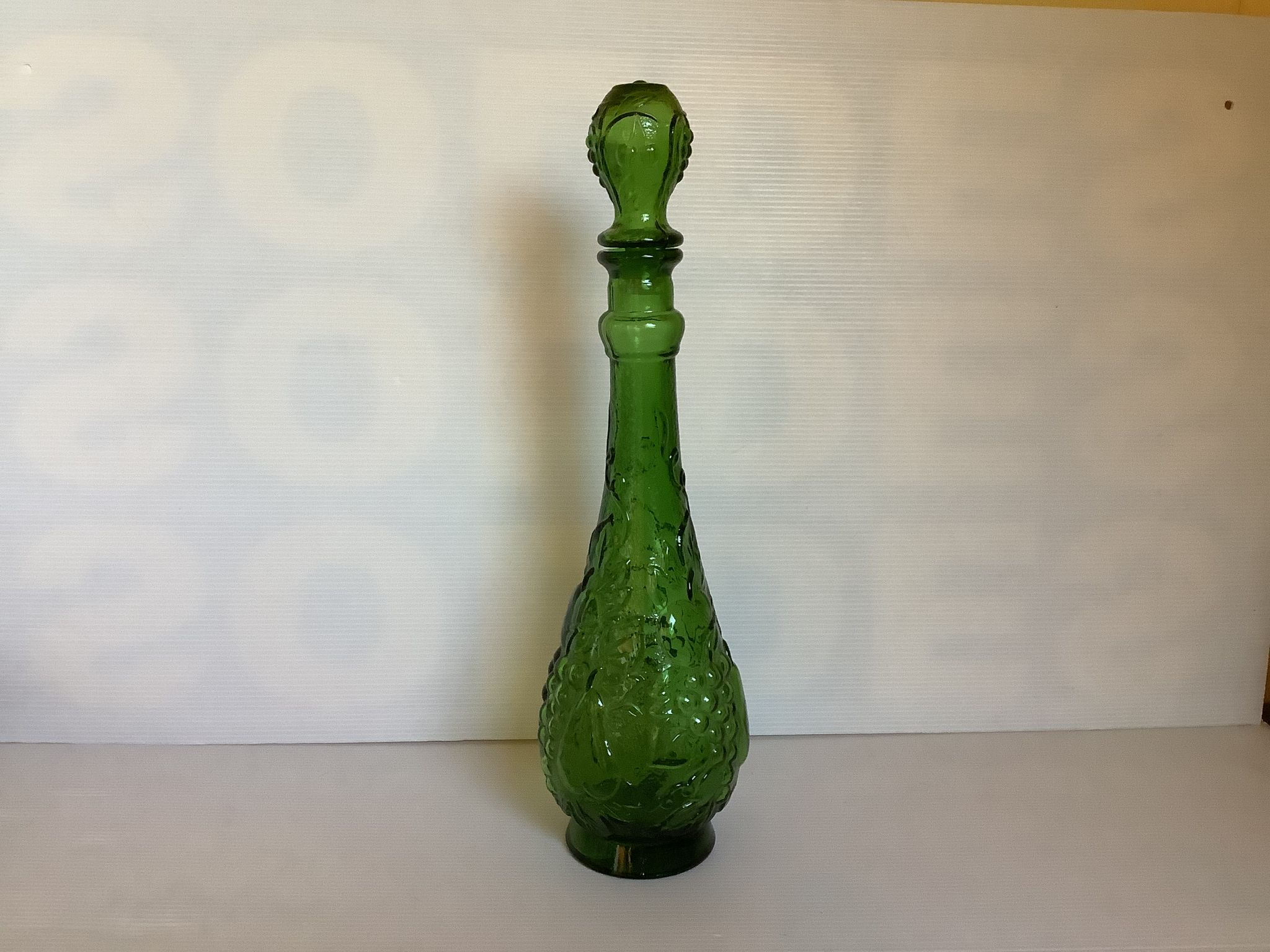 Green carafe bottle with apple, pear, and grape pattern from Italy.