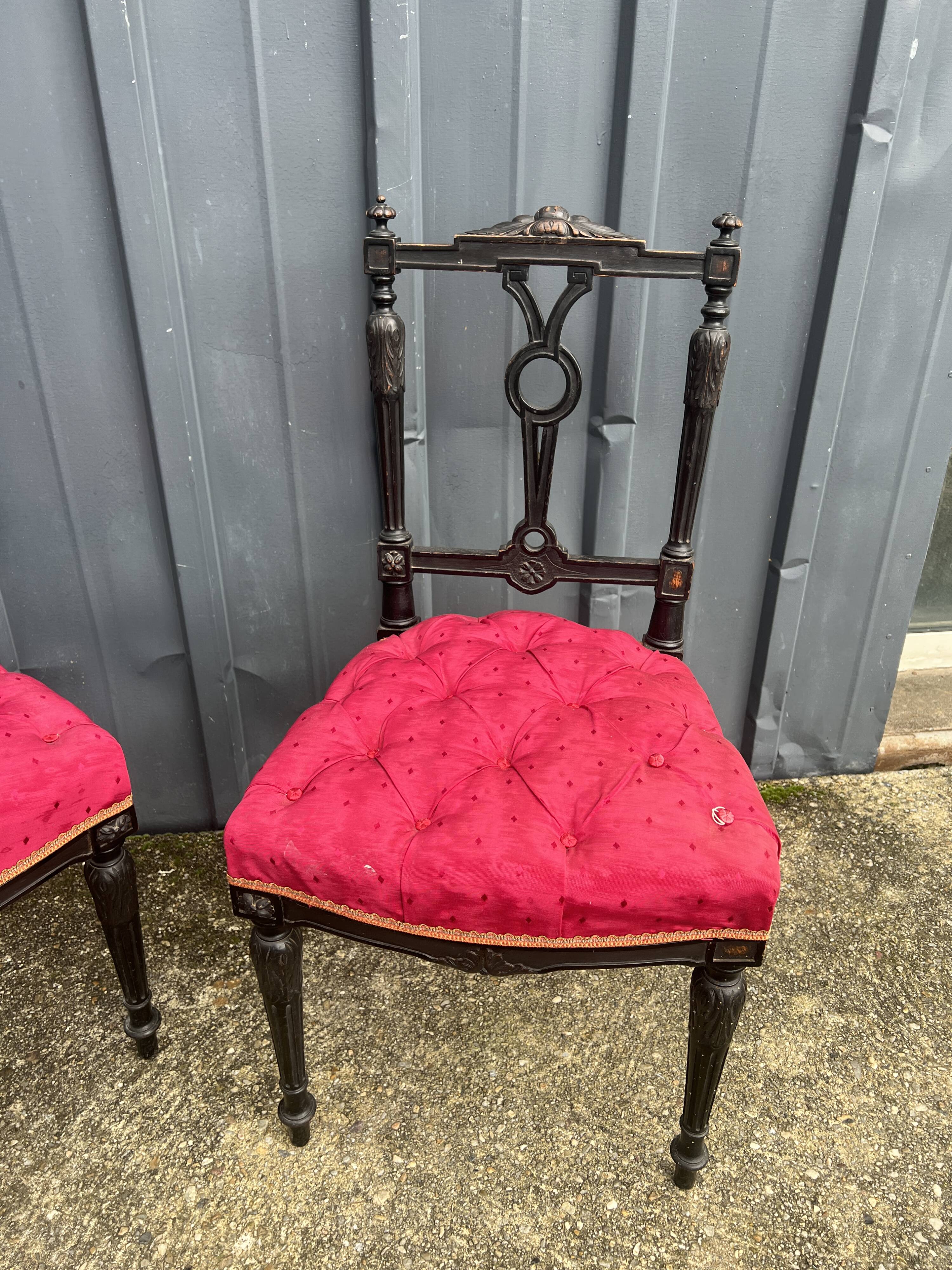 Pair of black lacquered chairs with purple tufted upholstery.