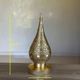 Handmade brass table lamp with a perforated drop-shaped shade.
