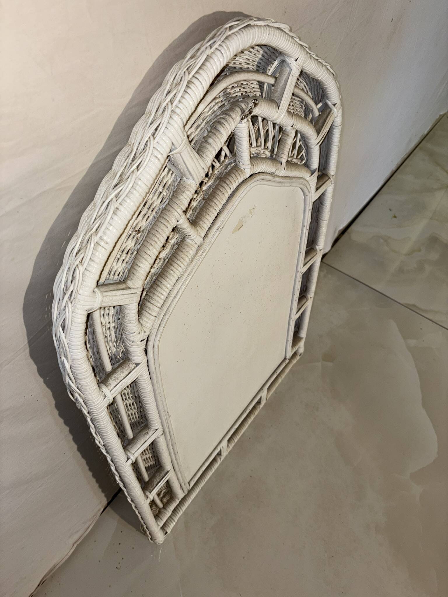 Vintage white rattan mirror with a gothic frame.