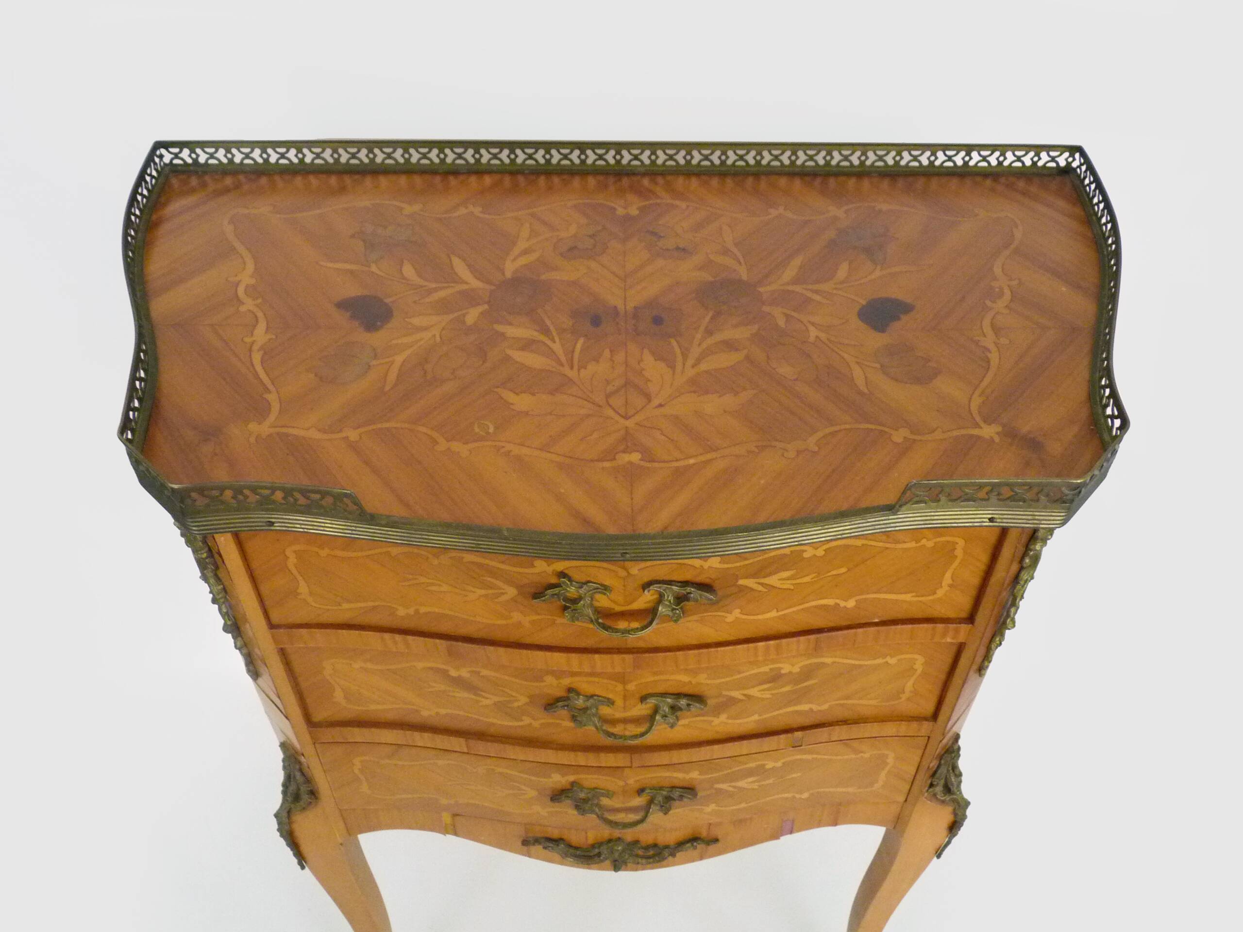 Baroque style wooden chest of drawers with bronze frieze.