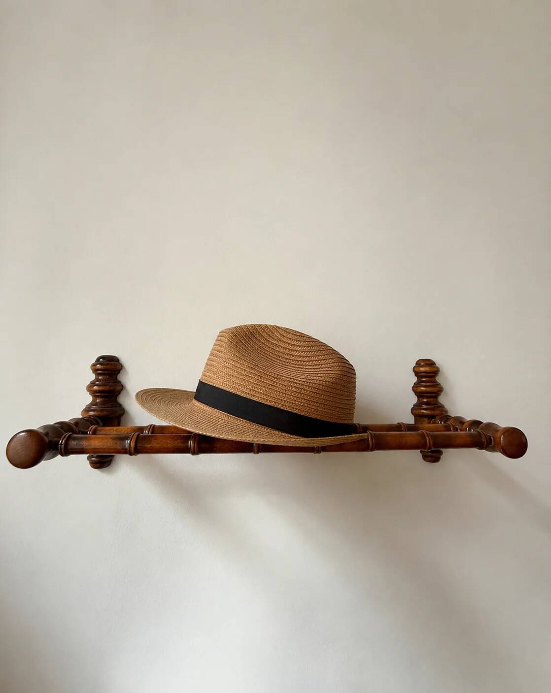 Wall-mounted coat rack made of turned wood in a bamboo style.
