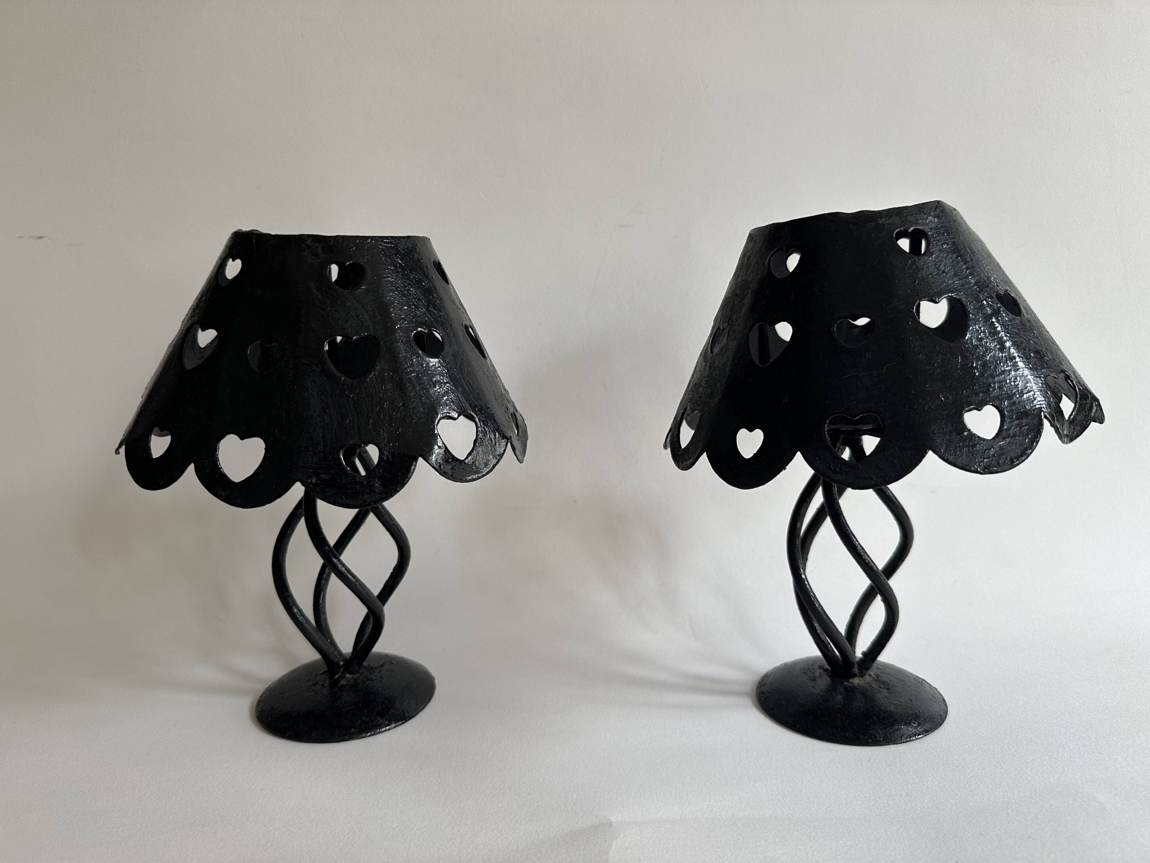 Pair of black wrought iron lanterns with heart patterns, romantic style.
