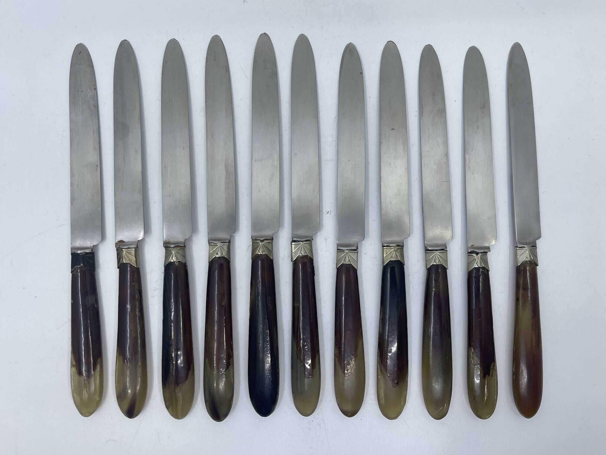 Set of 11 dessert knives with two-tone horn-effect resin handles.