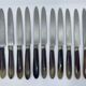 Set of 11 dessert knives with two-tone horn-effect resin handles.
