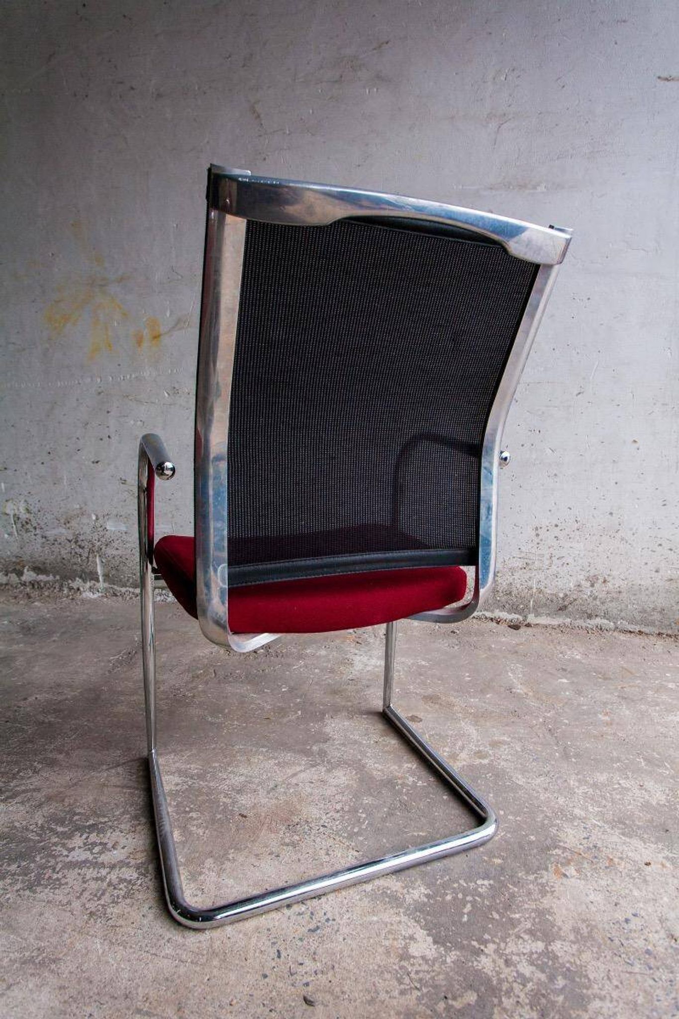 Set of 4 cantilever chairs with burgundy seat and mesh backrest.