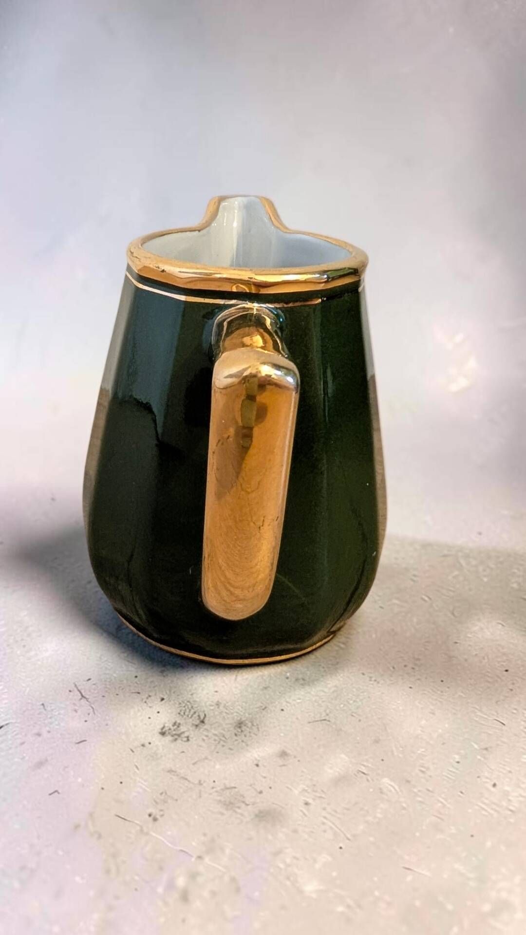 Dark green ceramic decorative jug with golden trim.