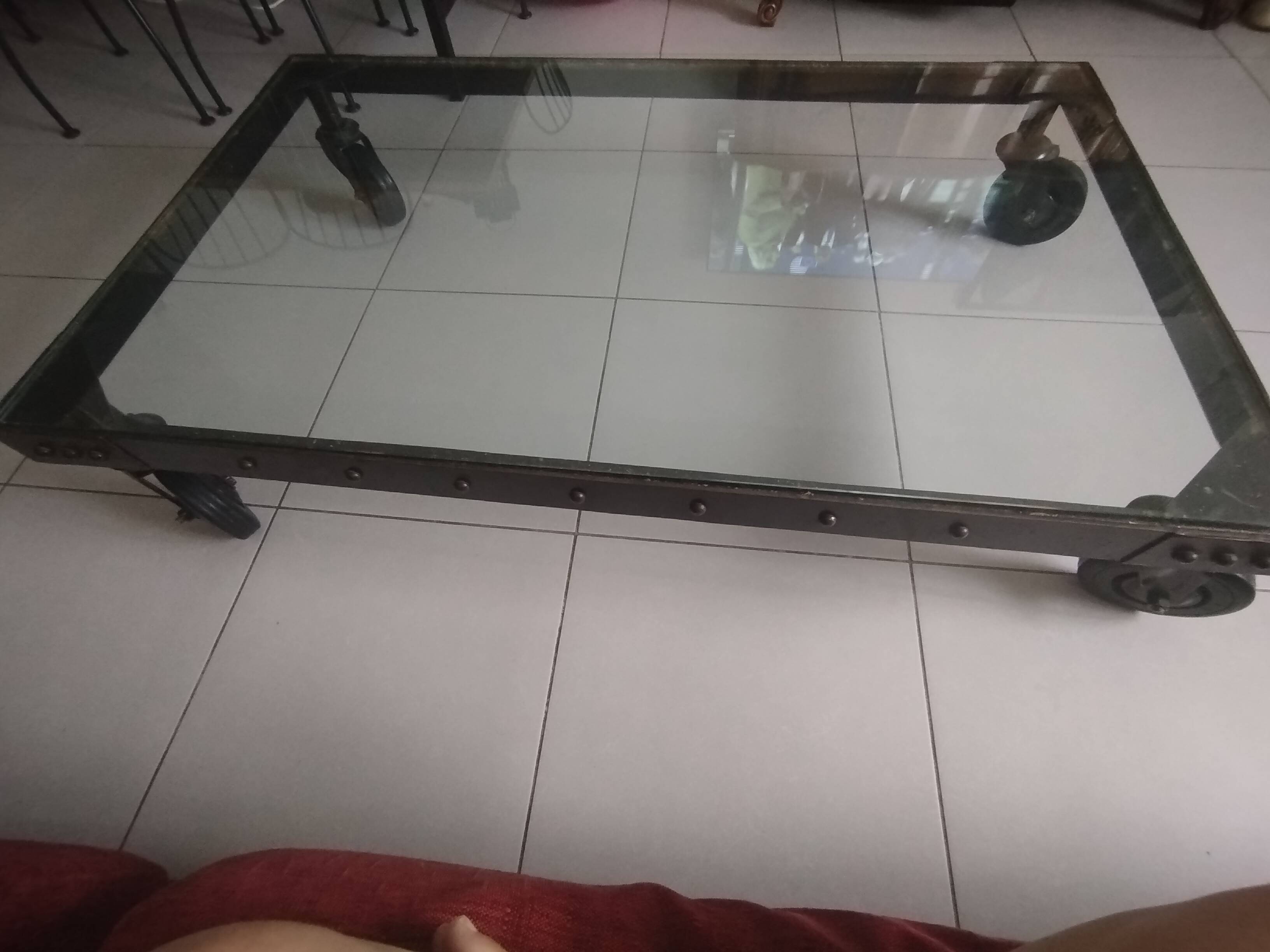 Industrial coffee table in solid metal with a glass top.