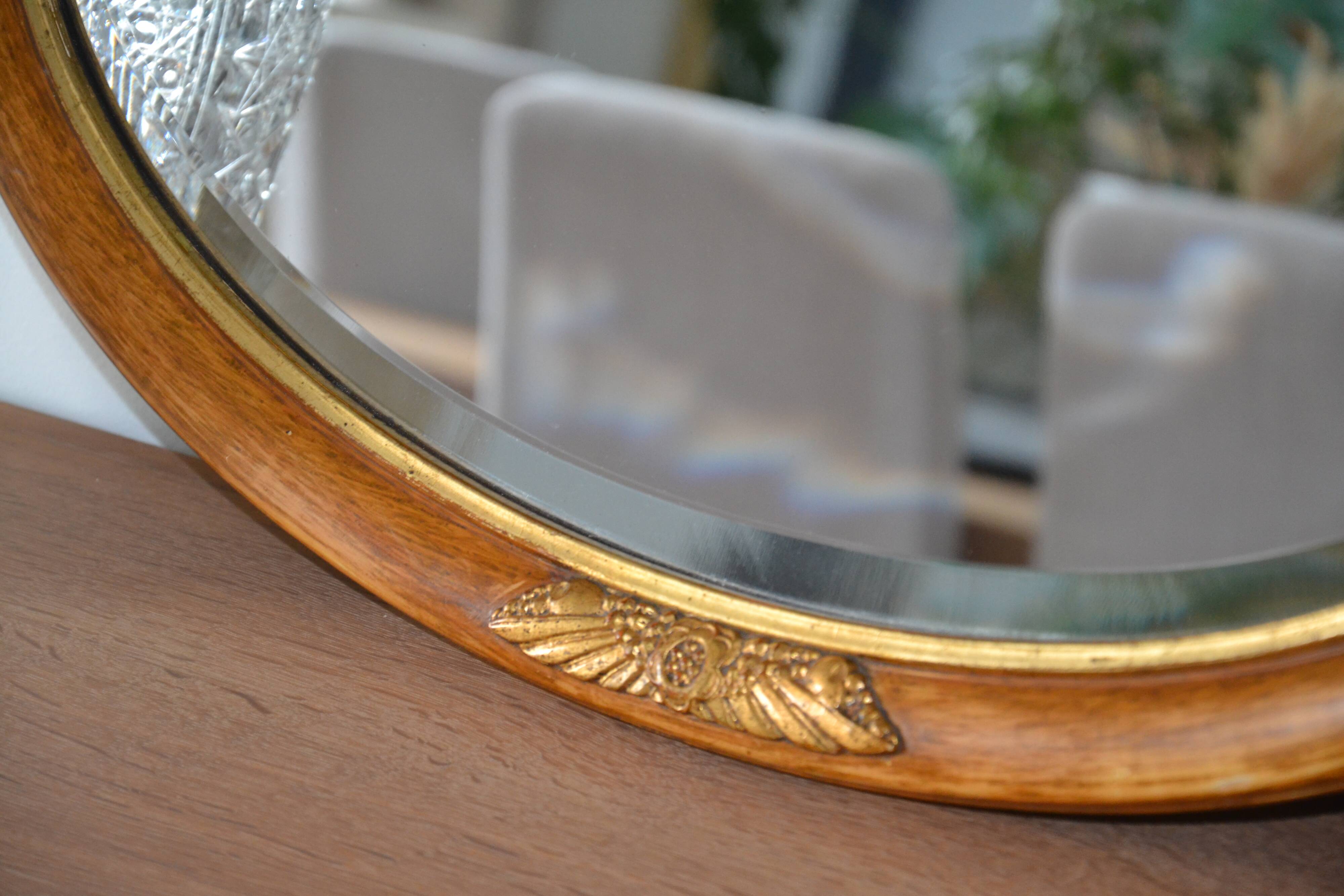 Old oval beveled wooden mirror, partly gilded and carved